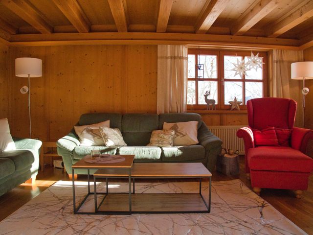 Wohnzimmer mit grünem Sofa, rotem Ohrensessel und Holzvertäfelung