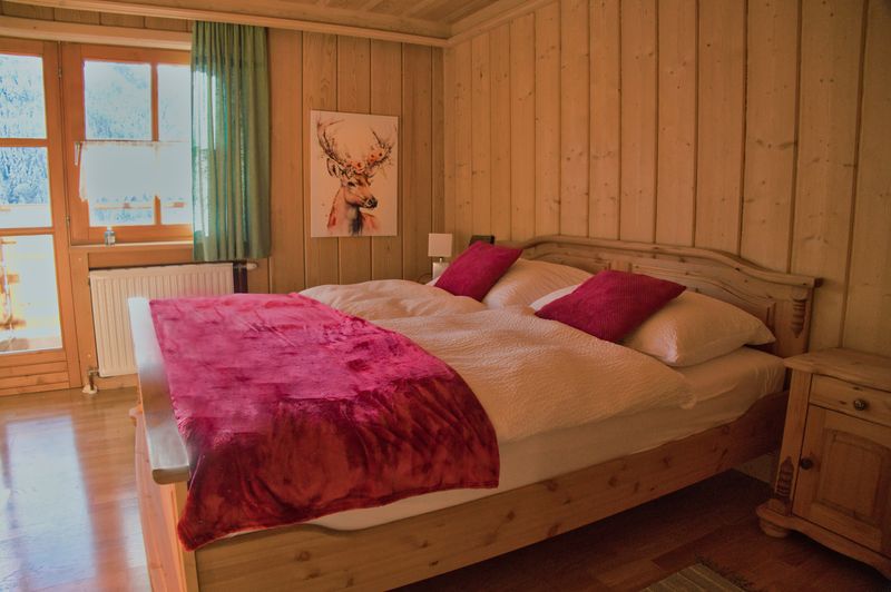 Tweepersoonskamer met houten bed en rode sprei