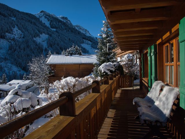 Holzbalkon mit Bank und Blick auf die verschneiten Berge