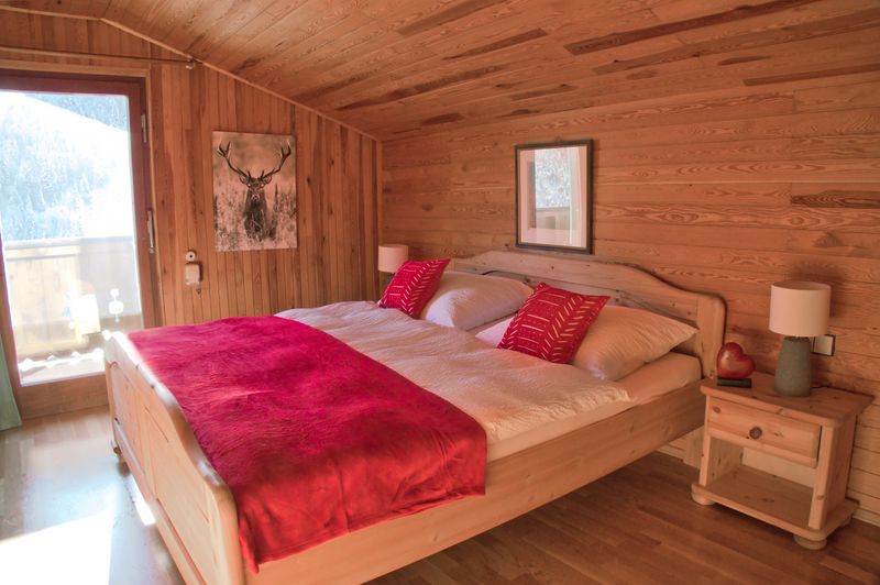 Slaapkamer met tweepersoonsbed, hertenschilderij en balkondeur