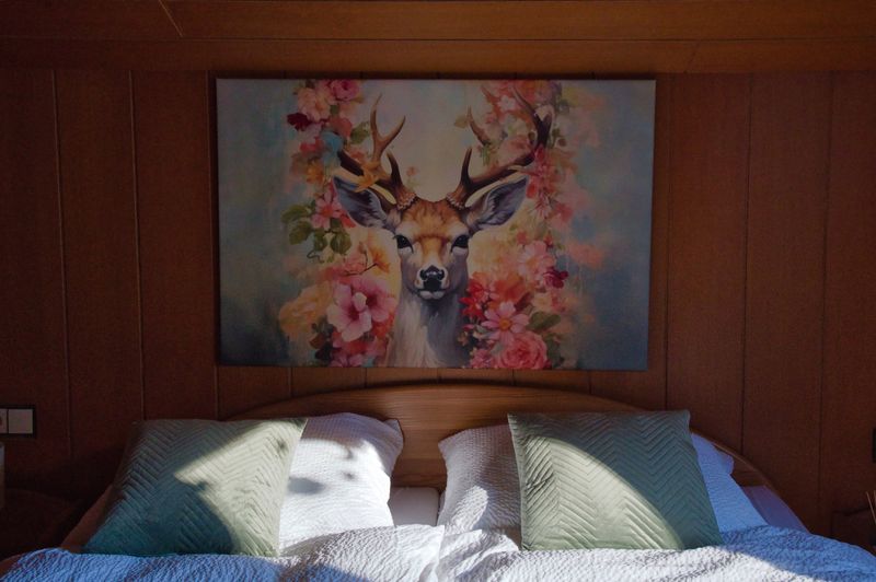 Tweepersoonsbed met kleurrijk hertenschilderij aan de muur