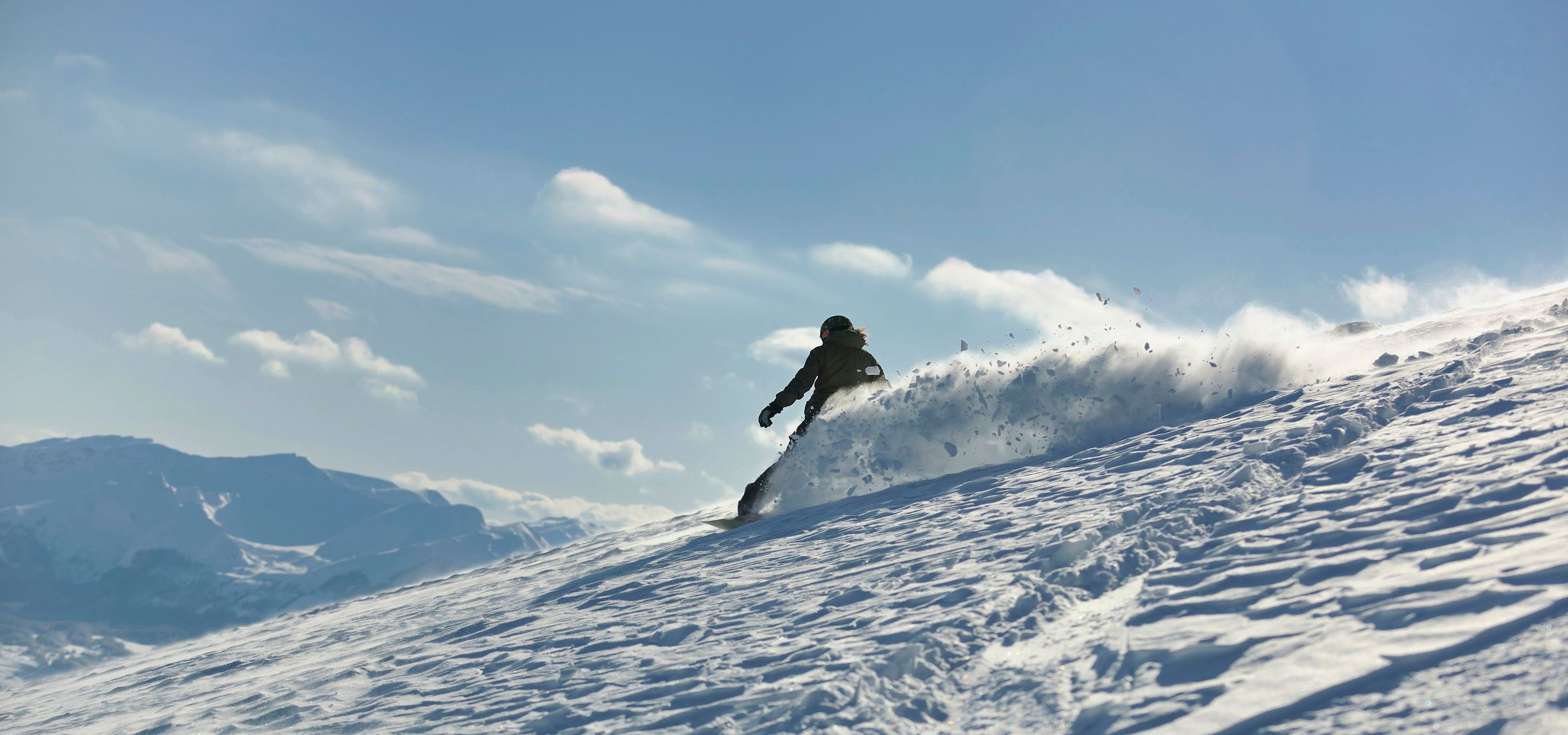 Snowboarder im Tiefschnee vor Bergpanorama