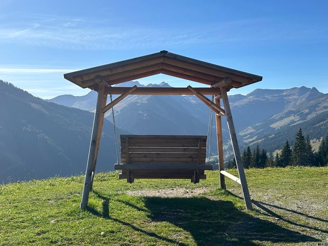 Hollywoodschaukel auf einer Almwiese mit Bergblick