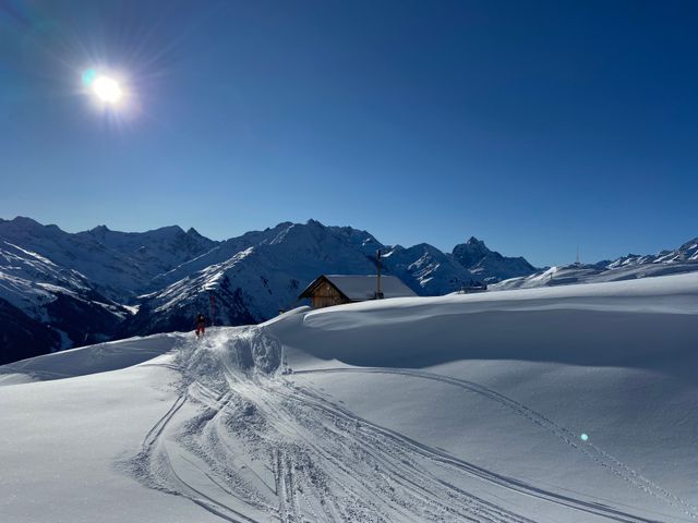 Verschneite Berglandschaft mit Skispuren in der Sonne