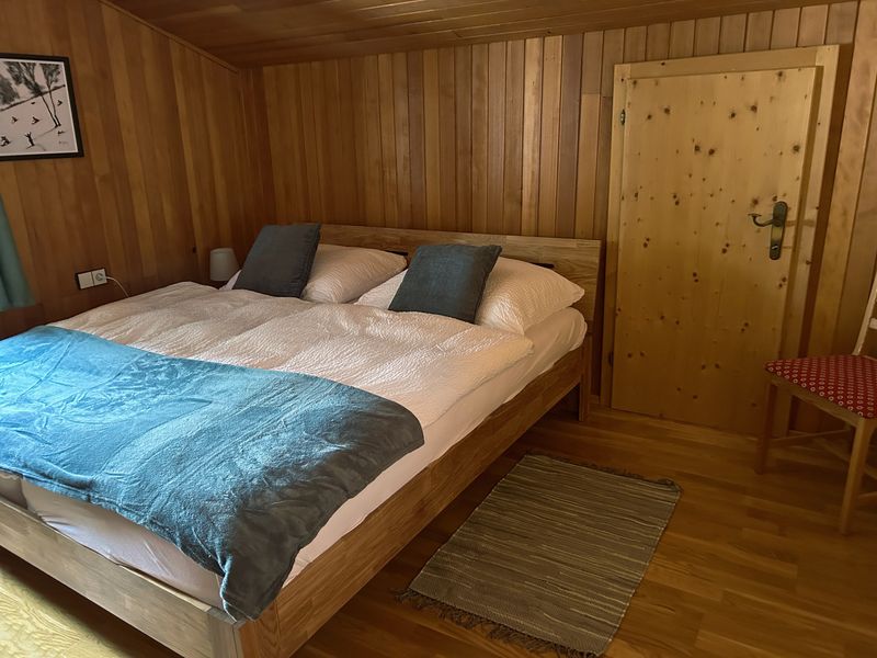 Tweepersoonskamer met houten bed en blauw beddengoed