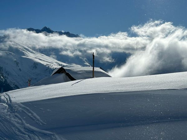 Tief verschneite Alm über dem Nebelmeer