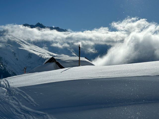 Tief verschneite Alm über dem Nebelmeer